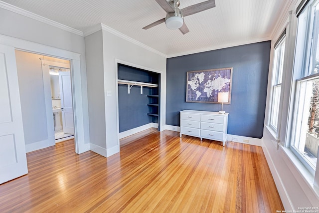 unfurnished bedroom featuring a closet, crown molding, light wood-type flooring, and baseboards