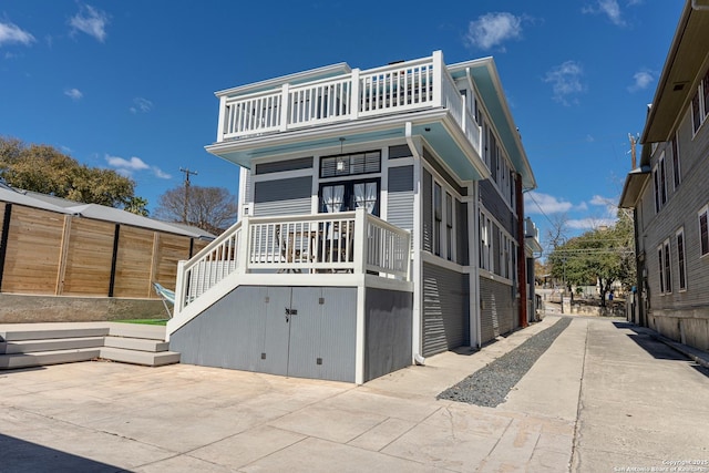 view of front of property with covered porch, a balcony, and fence