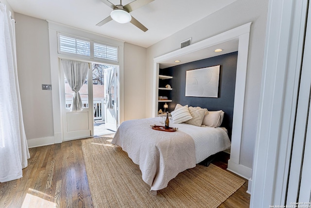 bedroom featuring visible vents, baseboards, wood finished floors, a ceiling fan, and access to outside