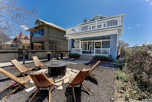 rear view of house with a balcony, fence, an outdoor fire pit, covered porch, and ceiling fan