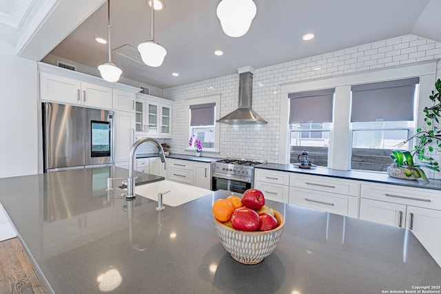 kitchen featuring dark countertops, visible vents, stainless steel appliances, white cabinetry, and wall chimney exhaust hood