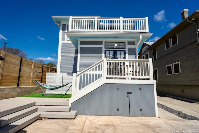 back of property with a deck, a patio area, a balcony, and fence