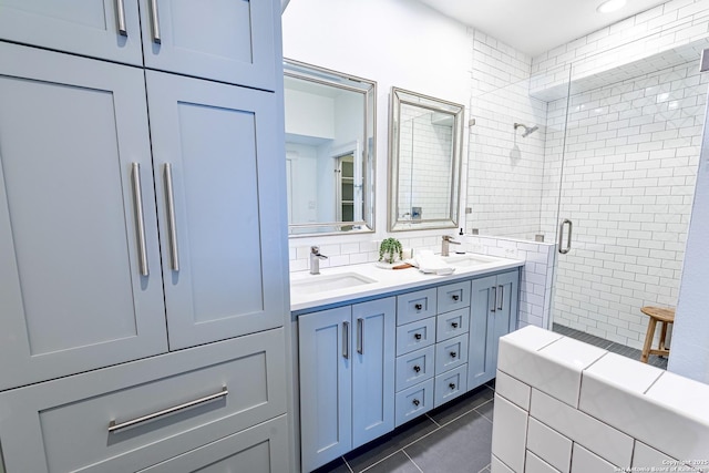 bathroom featuring tile patterned flooring, a shower stall, double vanity, and a sink