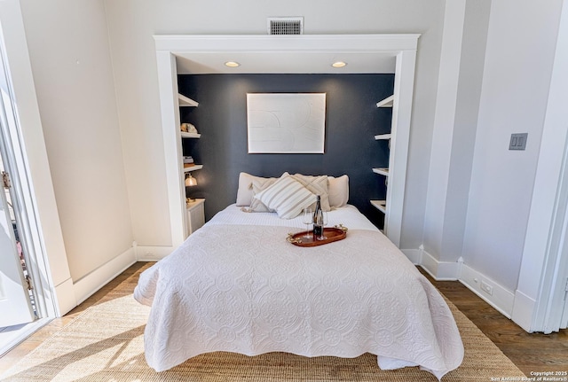 bedroom with visible vents, baseboards, and wood finished floors