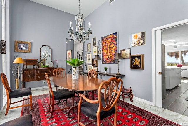 dining room featuring a chandelier, marble finish floor, baseboards, and a towering ceiling