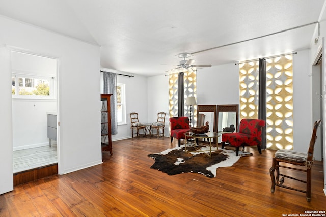 living area with hardwood / wood-style flooring, baseboards, and ceiling fan