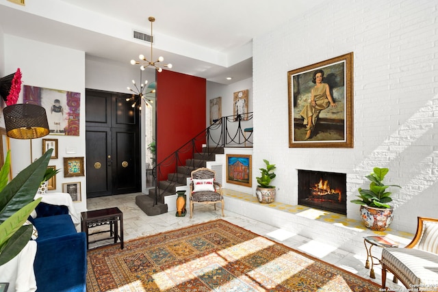 living area featuring stairway, visible vents, a fireplace, a notable chandelier, and marble finish floor