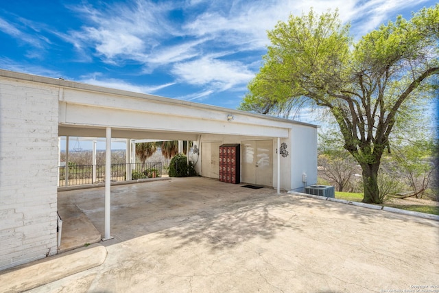 exterior space featuring a carport, central air condition unit, and concrete driveway