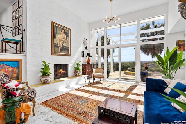 living room featuring a notable chandelier, marble finish floor, a towering ceiling, and a fireplace