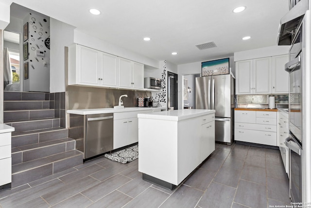 kitchen with visible vents, light countertops, decorative backsplash, white cabinets, and stainless steel appliances