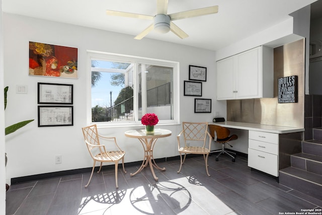 office space featuring baseboards, ceiling fan, and built in study area