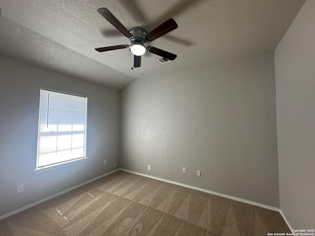 carpeted empty room featuring baseboards, visible vents, a textured ceiling, and a ceiling fan