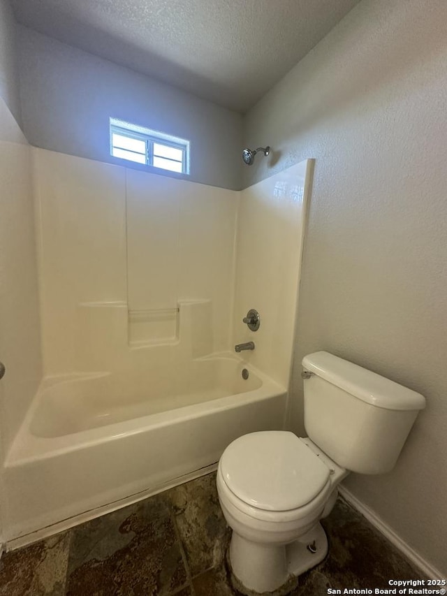 full bathroom featuring shower / washtub combination, a textured ceiling, toilet, and baseboards