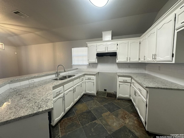 kitchen with light stone countertops, visible vents, a sink, white cabinetry, and backsplash