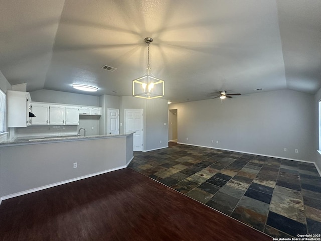 kitchen with visible vents, a ceiling fan, white cabinetry, a peninsula, and vaulted ceiling