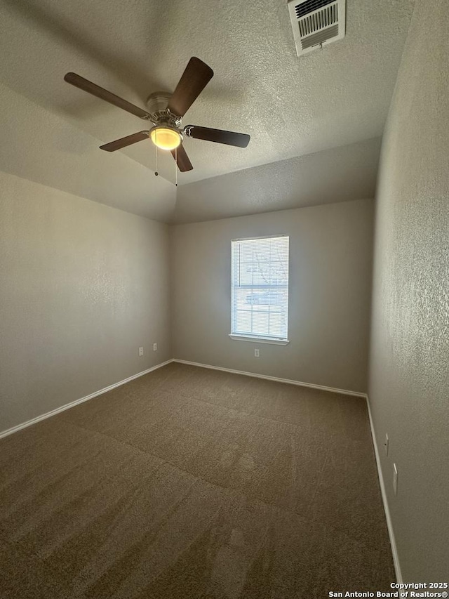 spare room featuring baseboards, visible vents, ceiling fan, a textured ceiling, and dark carpet