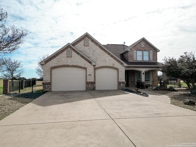 view of front of home with driveway, stone siding, fence, a garage, and brick siding