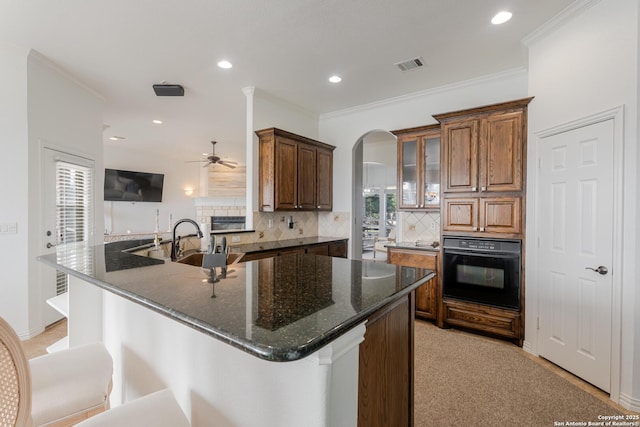 kitchen featuring visible vents, ceiling fan, crown molding, black oven, and backsplash