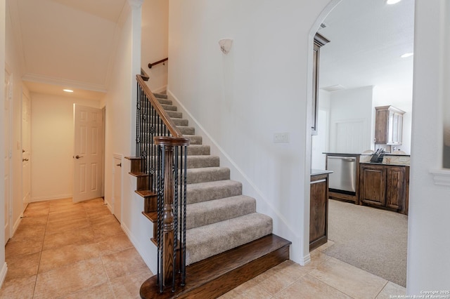 stairway with baseboards, arched walkways, carpet, and tile patterned flooring