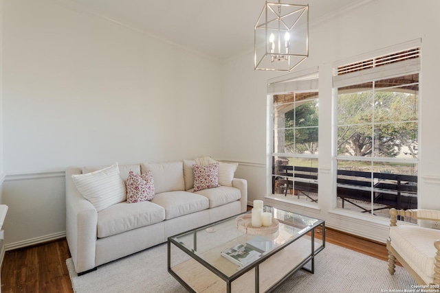 living area featuring wood finished floors, a notable chandelier, and ornamental molding