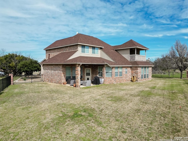 rear view of house with a balcony, a yard, and a fenced backyard