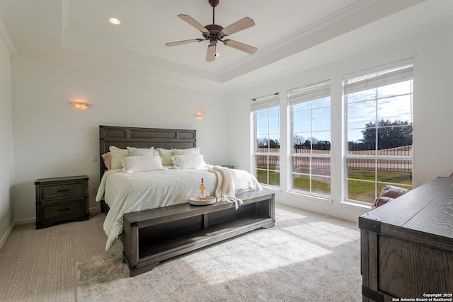 carpeted bedroom with a raised ceiling, baseboards, and ornamental molding