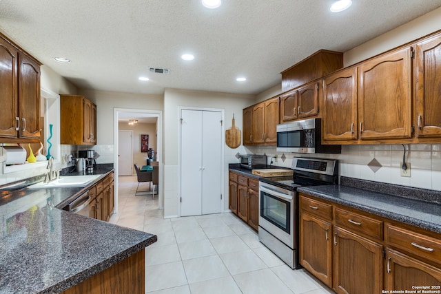 kitchen with a sink, dark countertops, visible vents, and stainless steel appliances