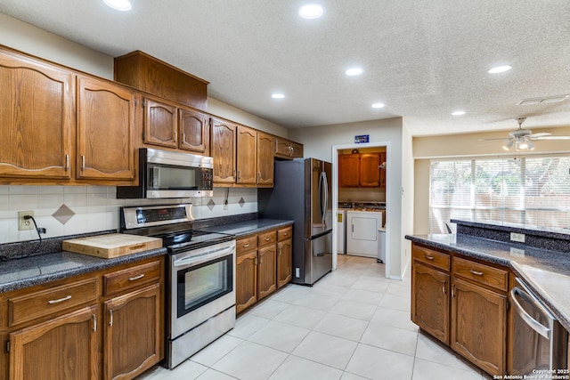 kitchen featuring washer and dryer, dark countertops, decorative backsplash, and stainless steel appliances