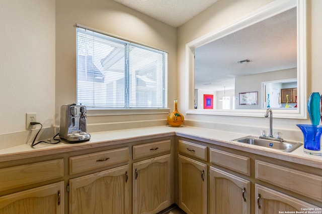 kitchen with visible vents, a textured ceiling, light countertops, and a sink