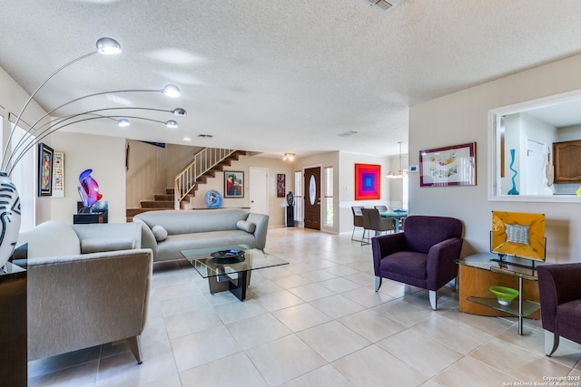 living area featuring stairs, light tile patterned floors, and a textured ceiling