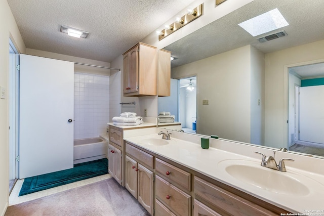 full bathroom with double vanity, a skylight, visible vents, and a sink