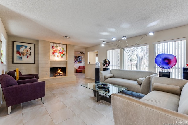 living room featuring light tile patterned floors, a fireplace, visible vents, and a textured ceiling