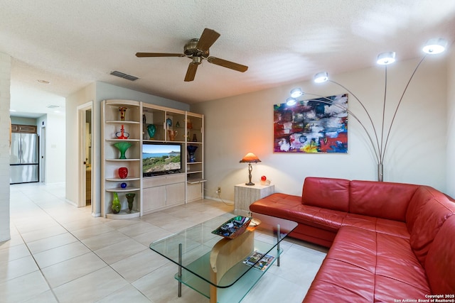 living room with visible vents, baseboards, ceiling fan, light tile patterned floors, and a textured ceiling