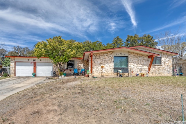 view of front facade with a front lawn, an attached garage, stone siding, and driveway