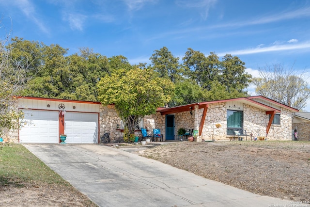 view of front of property with stone siding, driveway, and an attached garage