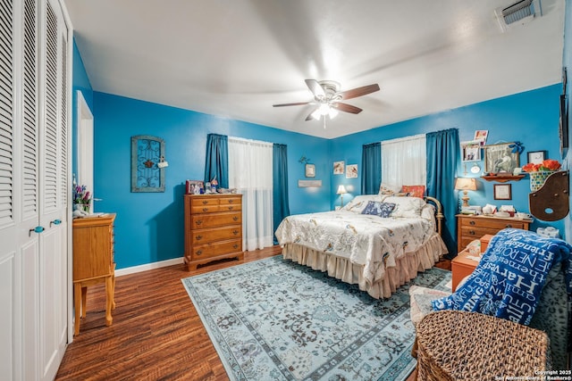 bedroom with wood finished floors, visible vents, baseboards, ceiling fan, and a closet