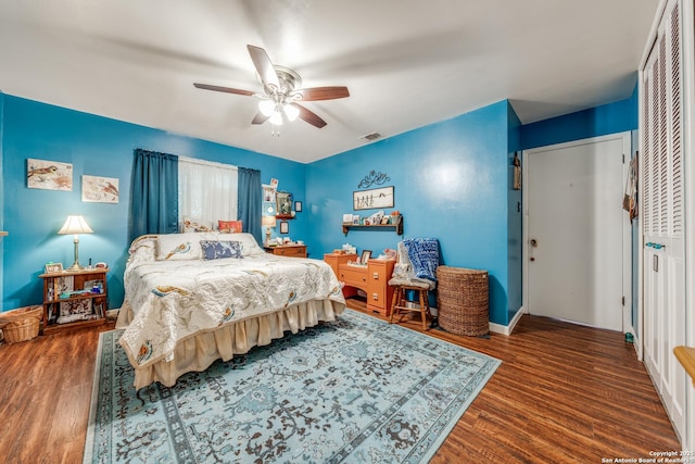 bedroom with a ceiling fan, wood finished floors, visible vents, and a closet