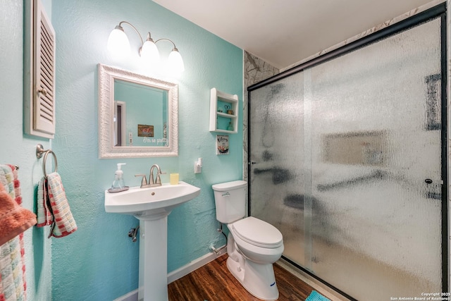 bathroom with wood finished floors, baseboards, a sink, a shower stall, and toilet