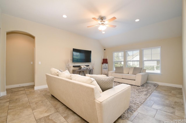 living area featuring vaulted ceiling, a ceiling fan, arched walkways, and baseboards