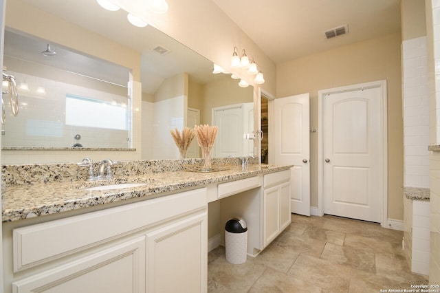 bathroom featuring a sink, visible vents, double vanity, and a tile shower