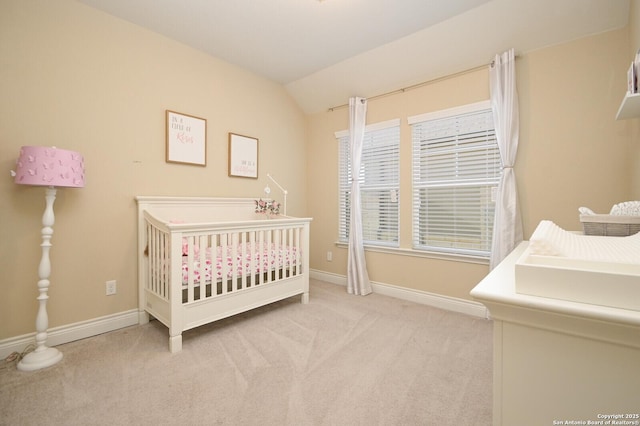 carpeted bedroom featuring baseboards, a crib, and lofted ceiling