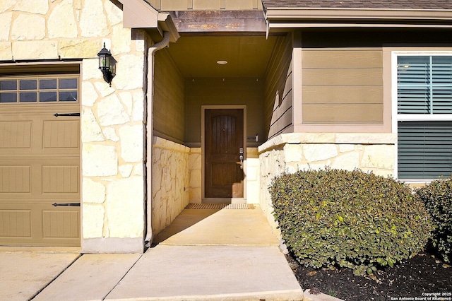 view of exterior entry featuring a garage and stone siding