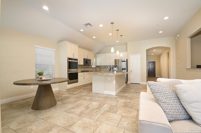 kitchen with a center island with sink, visible vents, arched walkways, stainless steel appliances, and white cabinets