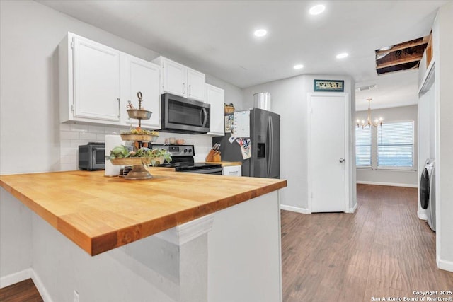 kitchen featuring backsplash, washer / dryer, a peninsula, a notable chandelier, and stainless steel appliances