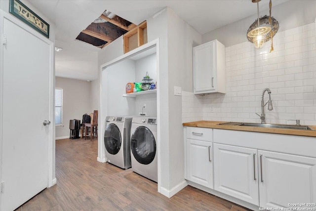 washroom featuring baseboards, light wood-type flooring, laundry area, separate washer and dryer, and a sink