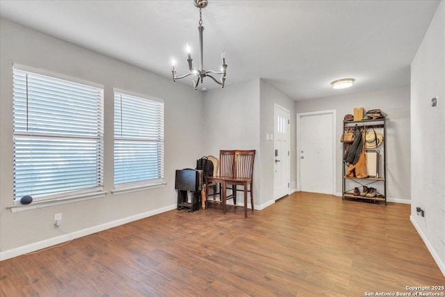 interior space with a notable chandelier, wood finished floors, and baseboards