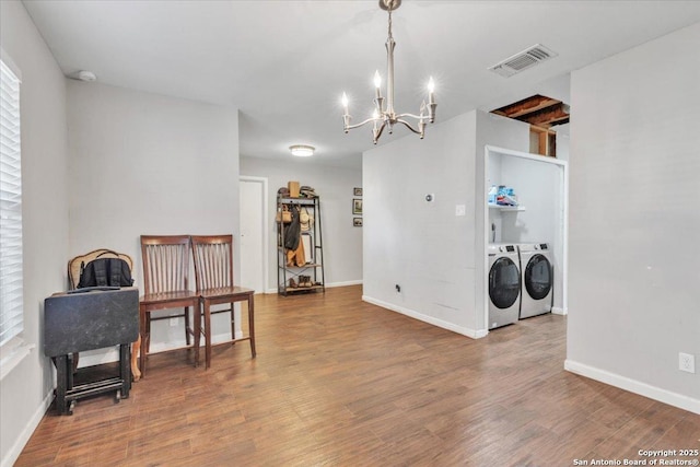 interior space featuring visible vents, baseboards, a chandelier, wood finished floors, and washer and dryer