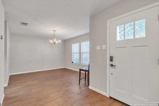 entrance foyer with visible vents, wood finished floors, baseboards, and a chandelier