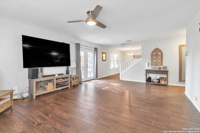 living area with wood finished floors, baseboards, visible vents, a ceiling fan, and stairs