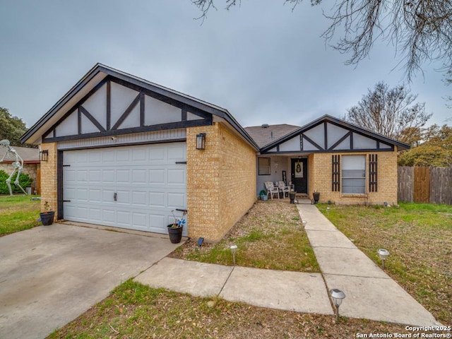 tudor house with an attached garage, fence, brick siding, and driveway